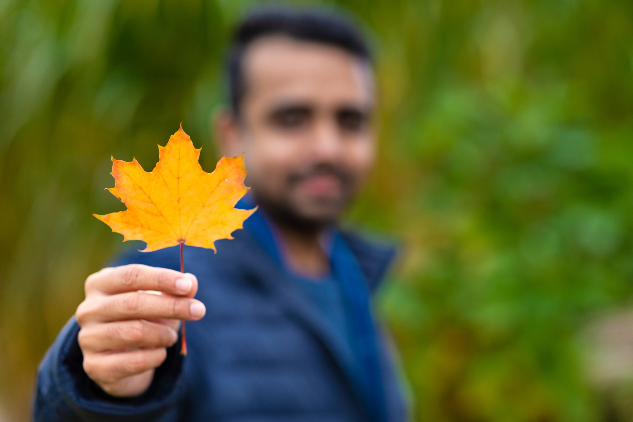 Welcome to Canada Selective focus image of an asian man holding a maple leaf